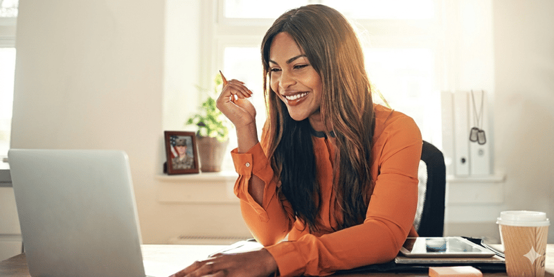 Individual smiling and working on laptop